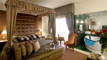 A bedroom with a four-poster bed, a sitting area with a small table, and a bathroom with a bathtub and a mirror.