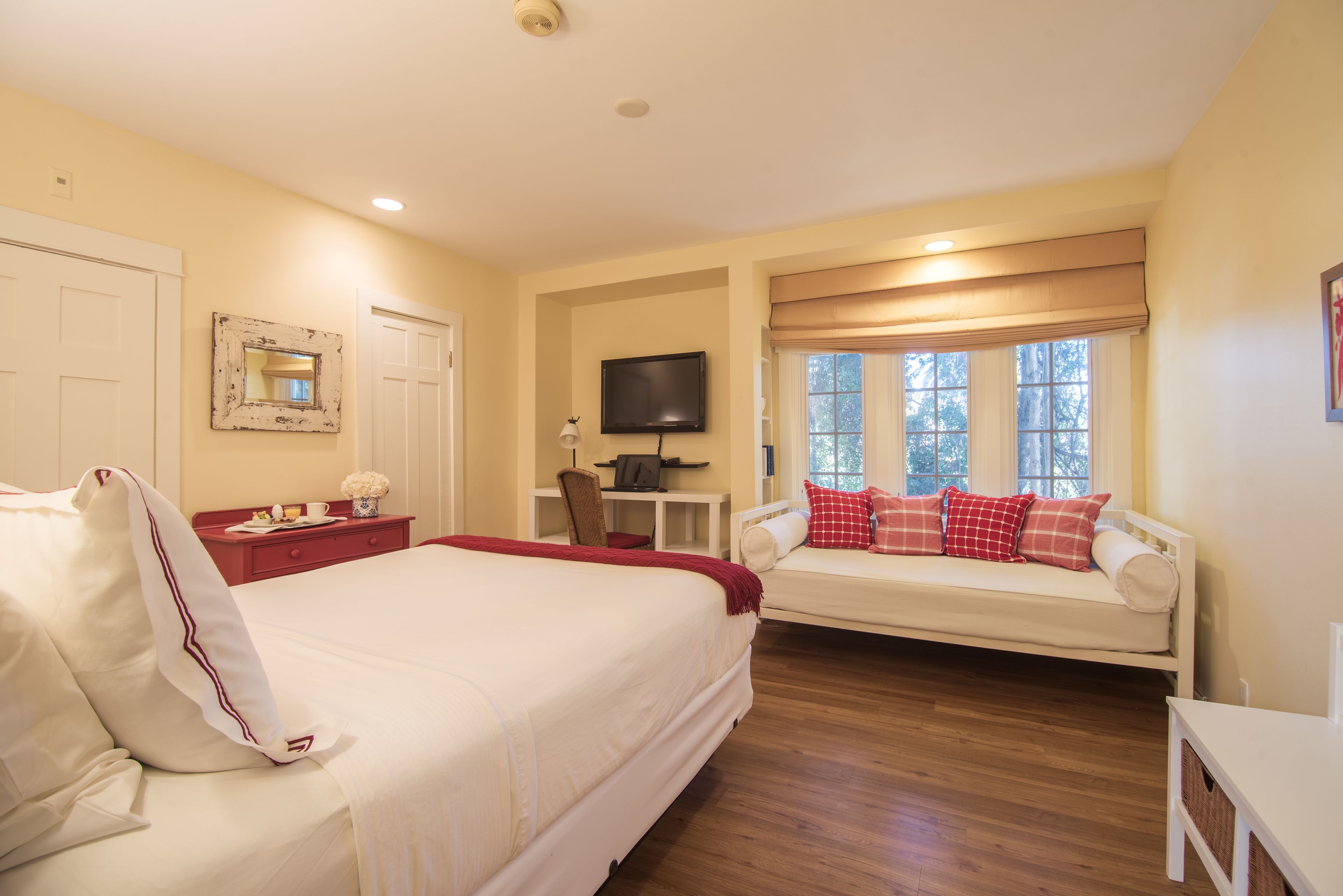 A hotel room with a large bed, a sofa, a television, and a desk.