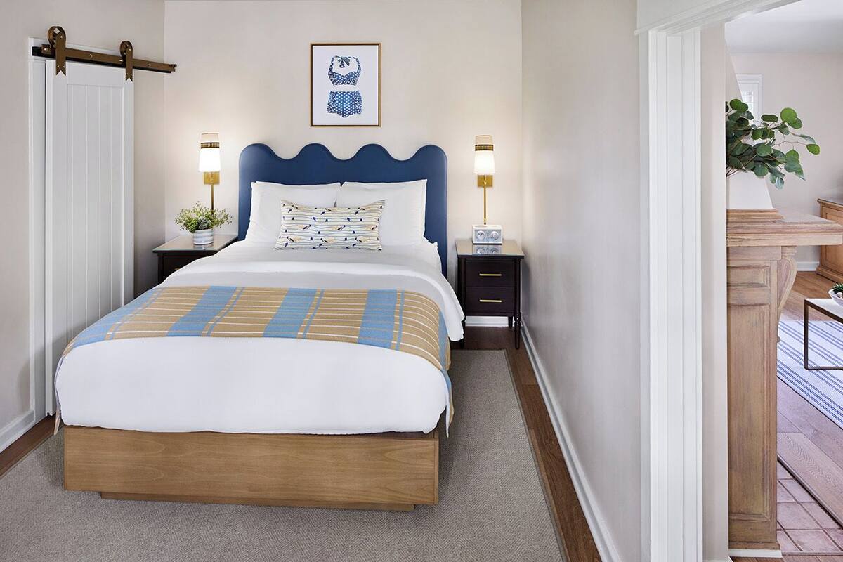 A neatly arranged bedroom with a large bed, two bedside tables, a wall-mounted lamp, and a framed picture above the bed.
