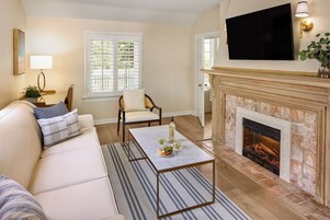 Una sala de estar con un sofá, una mesa de centro, una chimenea y un televisor montado en la pared.