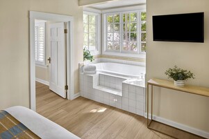 Un baño con bañera, lavamanos y ventana con vista a follaje.
