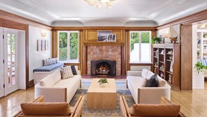A cozy living room with a fireplace, two sofas, a coffee table, and wooden flooring. - Channel Road Inn, A Four Sisters Inn (Santa Monica)