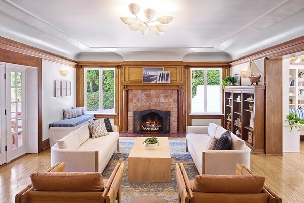 A cozy living room with a fireplace, two sofas, a coffee table, and wooden flooring.