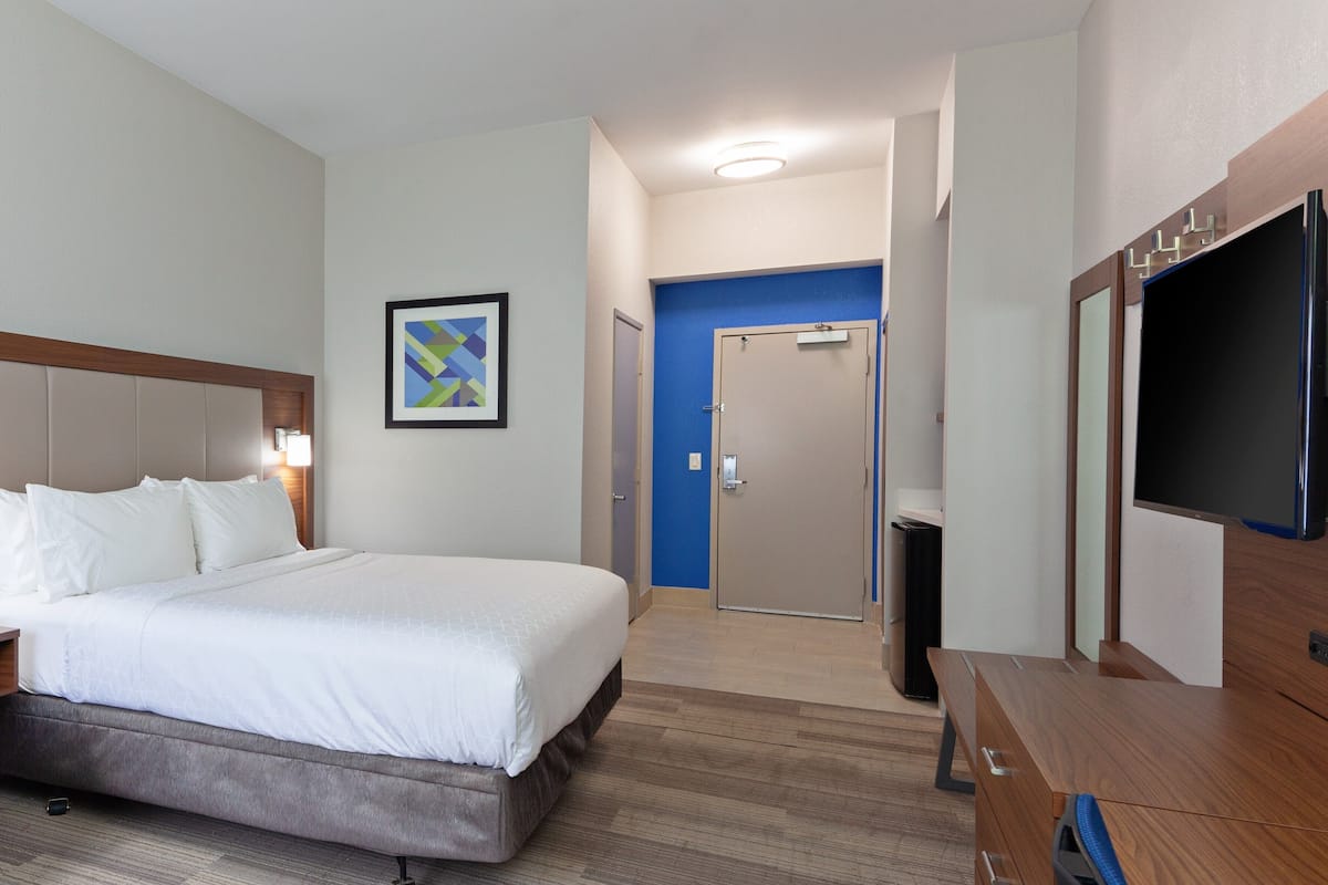 Une chambre d’hôtel avec un grand lit, une télévision, un bureau et une salle de bain visible à travers une porte ouverte.