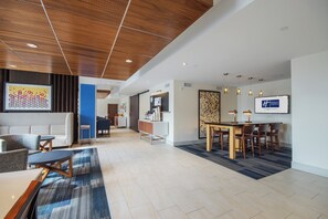 A hotel lobby with a reception desk, seating area, and a dining space.