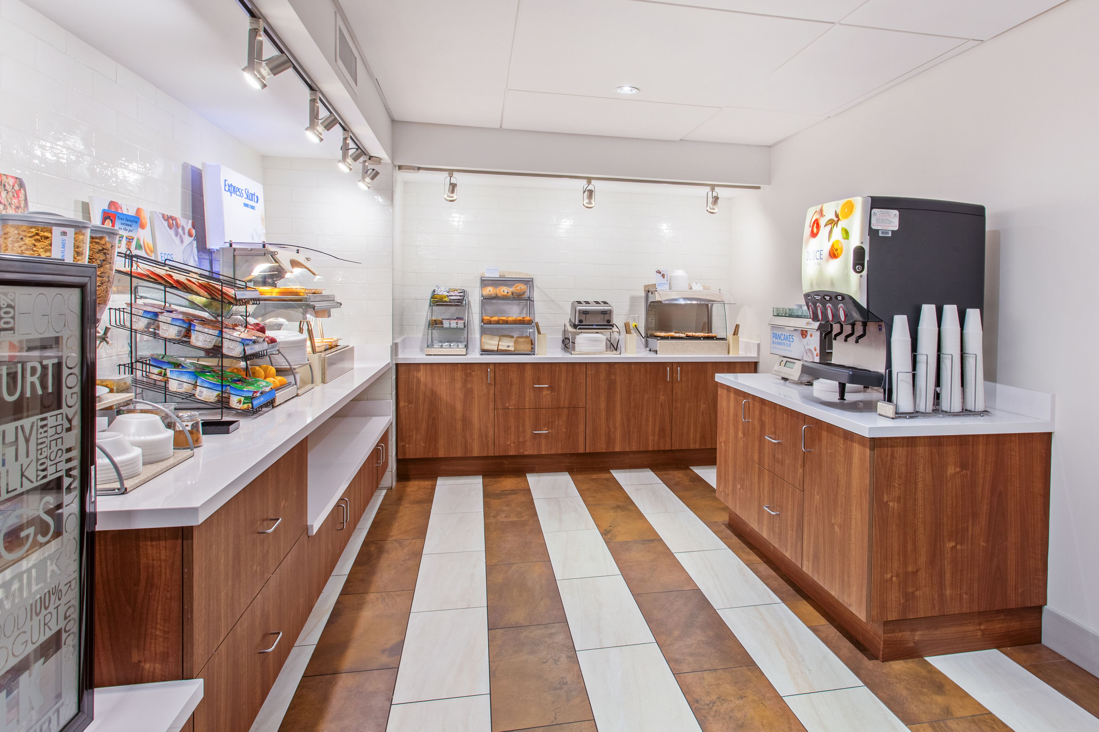 A modern kitchen with wooden cabinets, a coffee machine, and a variety of food items on display.
