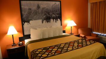 A hotel room with a large bed, two bedside tables with lamps, a chair, and a painting of horses on the wall.