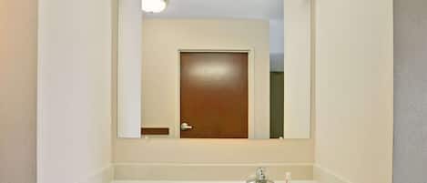 A bathroom with a white sink, a mirror, and a door.