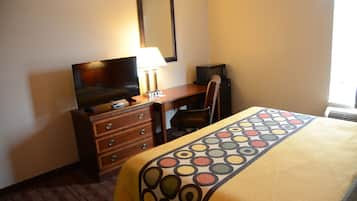 Una habitación de hotel con una cama, un escritorio con silla, un televisor y una lámpara.