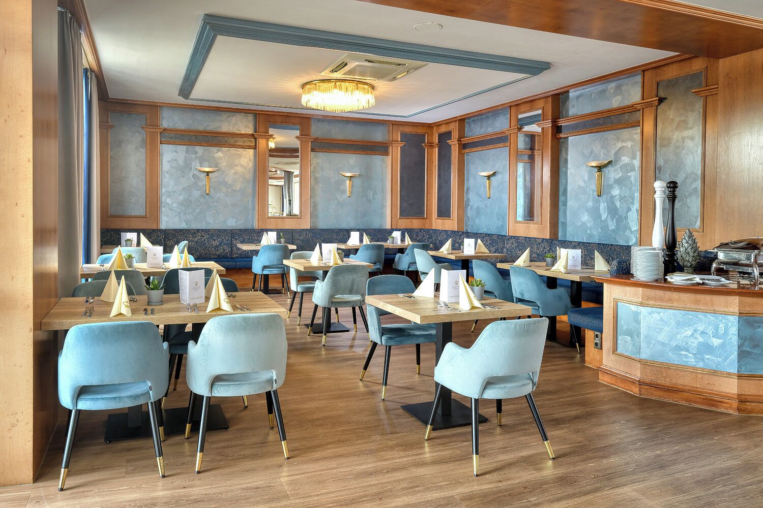 A restaurant with wooden paneling, blue chairs, and a central bar area.
