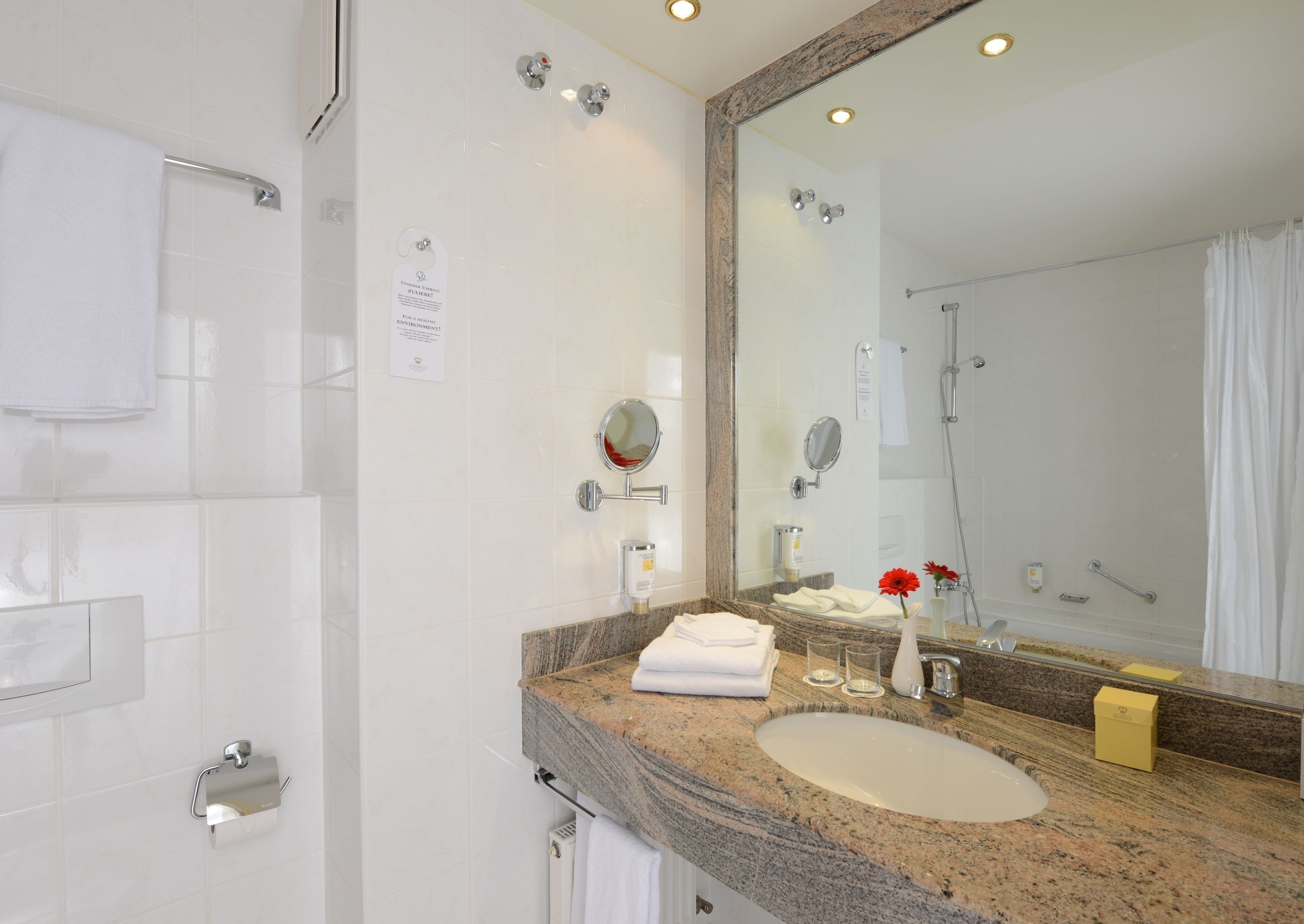 Une salle de bain moderne avec un plan de toilette en marbre, un lavabo, un miroir et une douche.
