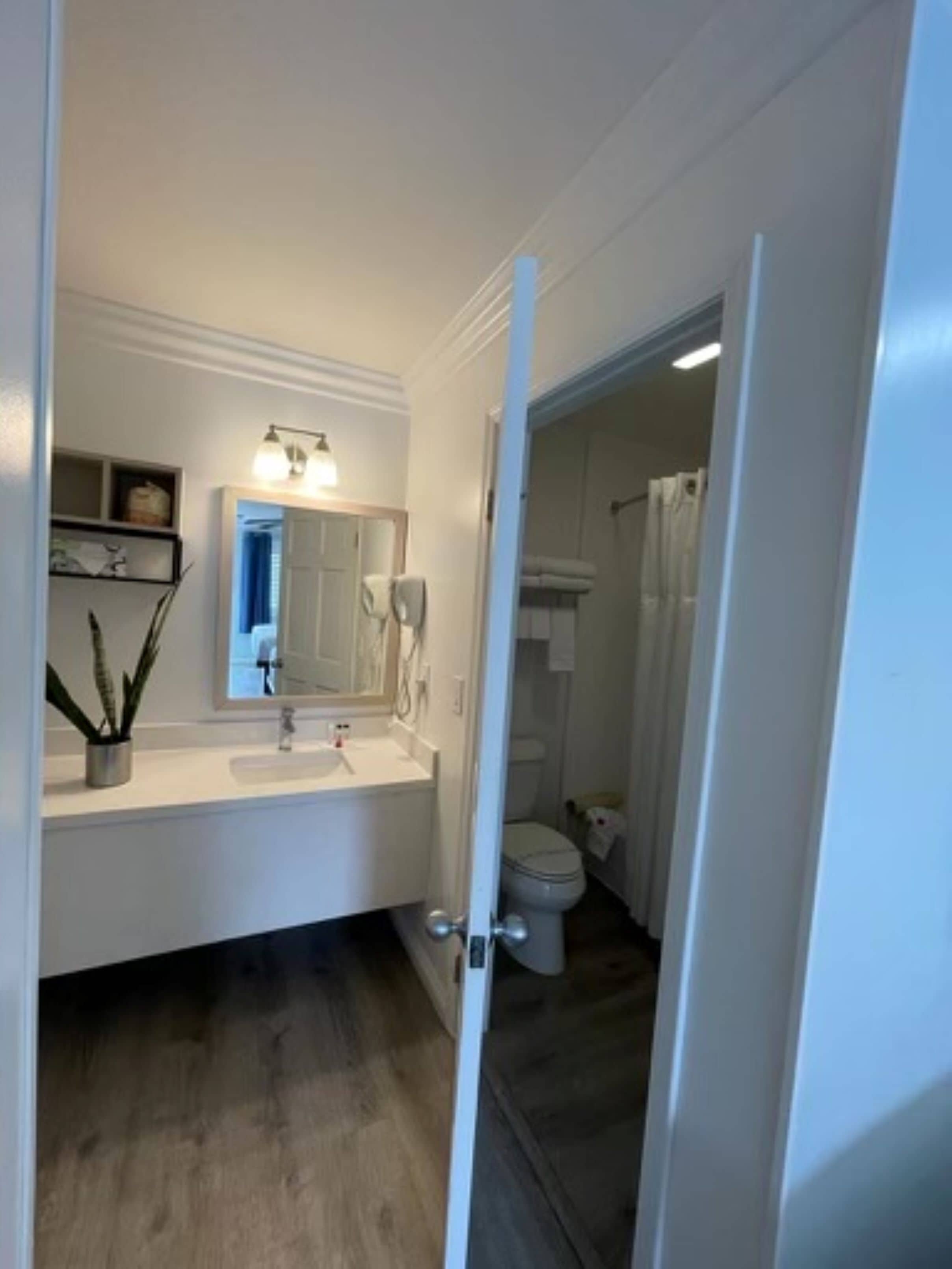Een moderne badkamer met een wit wastafelmeubilair, een spiegel en een toilet.