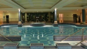 A large indoor swimming pool with multiple lanes, surrounded by tiled steps and railings. - The Galmont (Galway)