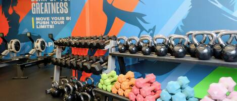 Un gimnasio con kettlebells, mancuernas y discos de pesas.