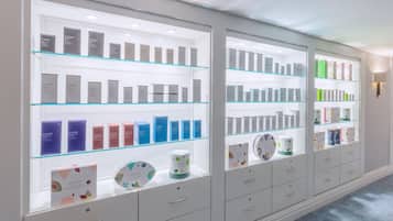Una presentación de productos de cuidado de la piel Elemis en un gabinete de vidrio bien iluminado, con varios estantes y cajones.