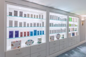 Una presentación de productos de cuidado de la piel Elemis en un gabinete de vidrio bien iluminado, con varios estantes y cajones.