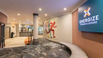 A hotel lobby with a large wall mural, a reception area, and a staircase.