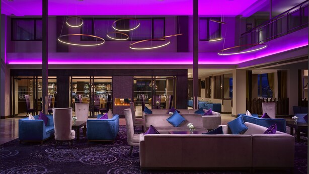 A modern lobby with a bar area, seating arrangements, and a view of the cityscape. - The Galmont (Galway)