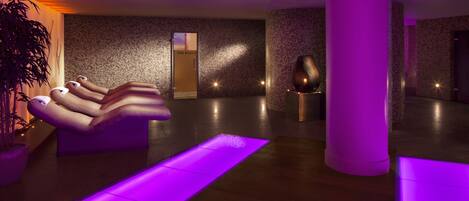 A spa area with a massage chair, a potted plant, and a reception desk.