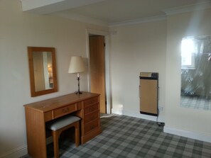 A room with a wooden desk, a mirror, a lamp, a wardrobe, and a checkered floor. - Windsor Hotel (Whitley Bay)