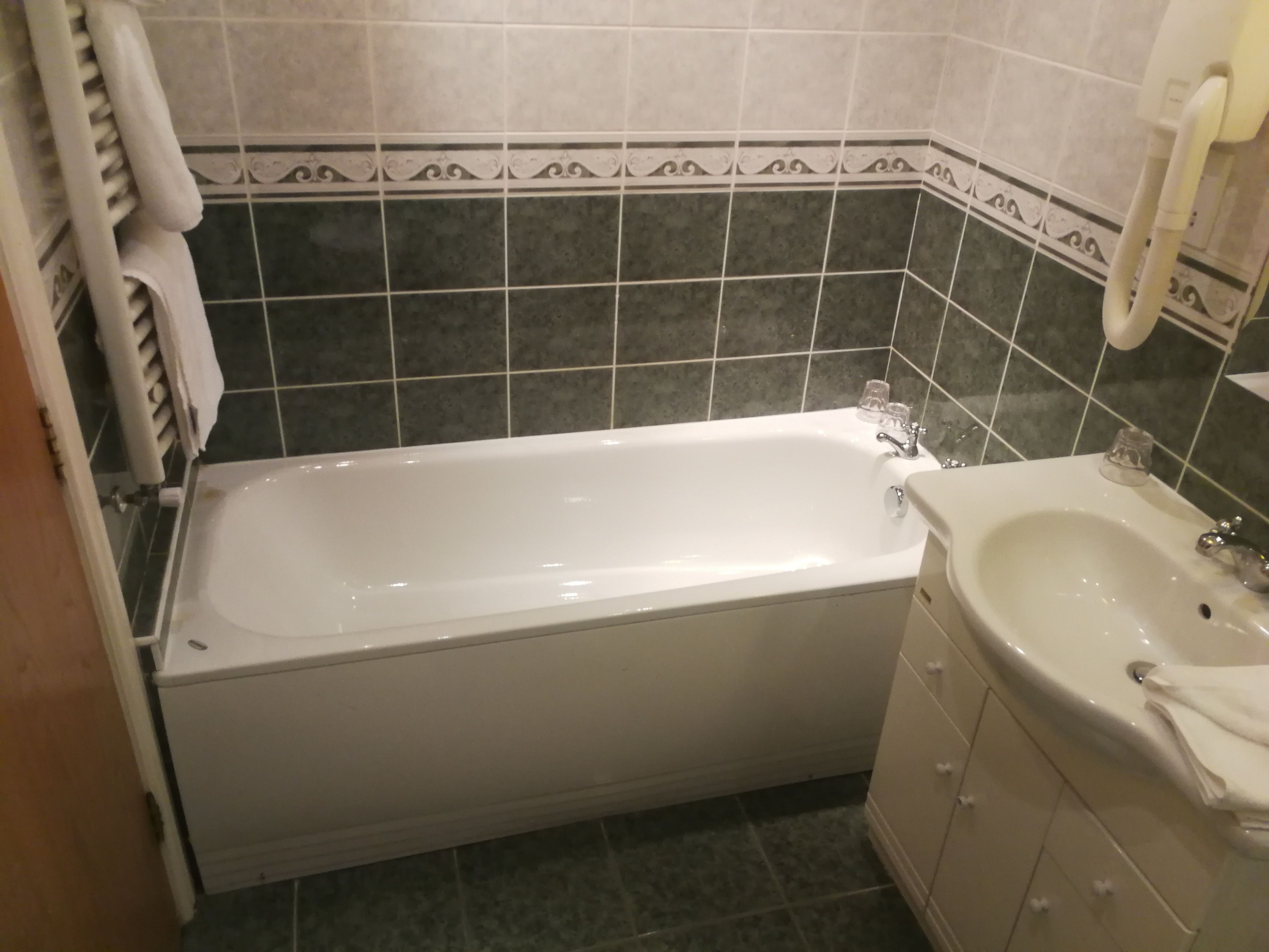 A bathroom with a bathtub, a sink, and a toilet. The walls are tiled with a decorative border.