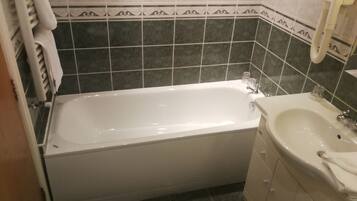 A bathroom with a bathtub, a sink, and a toilet. The walls are tiled with a decorative border.
