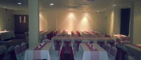 A banquet hall with rows of tables, each with a white tablecloth and red sashes.