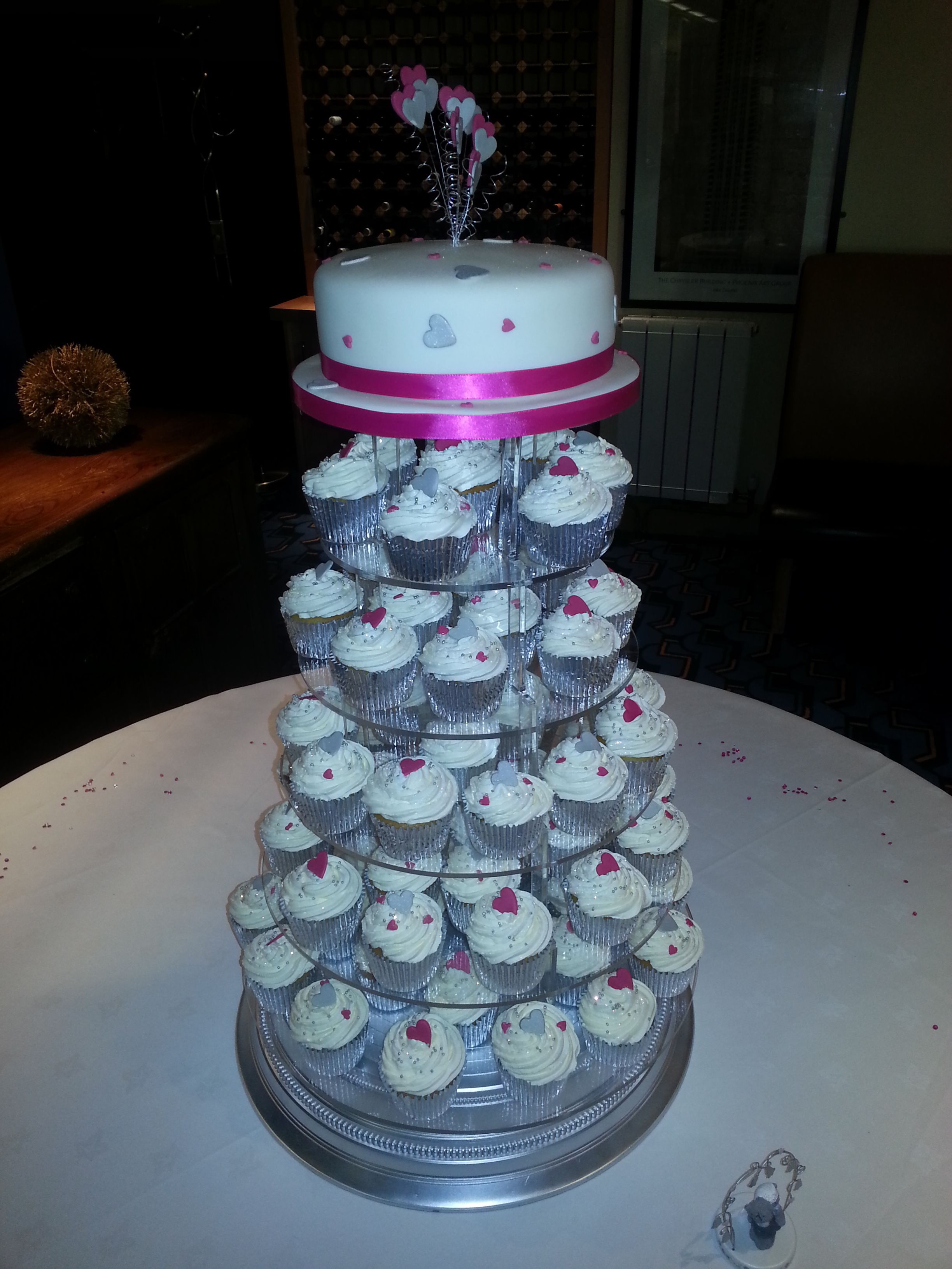 A tiered cake stand with cupcakes and a cake on top.