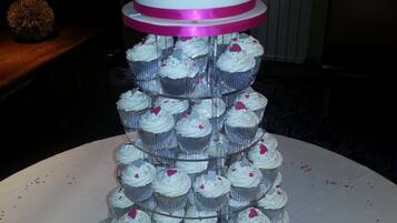 Un soporte escalonado para pasteles con cupcakes y un pastel encima.