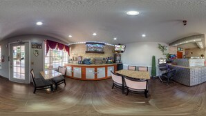 A spacious reception area with a curved counter, multiple seating options, and a large window with red curtains. - Carolina Lodge (Barnwell)