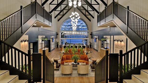 A spacious lobby with a central seating area, a staircase, and a large arched window offering a view. - Courtyard Hotel Gqeberha (Gqeberha (Port Elizabeth))