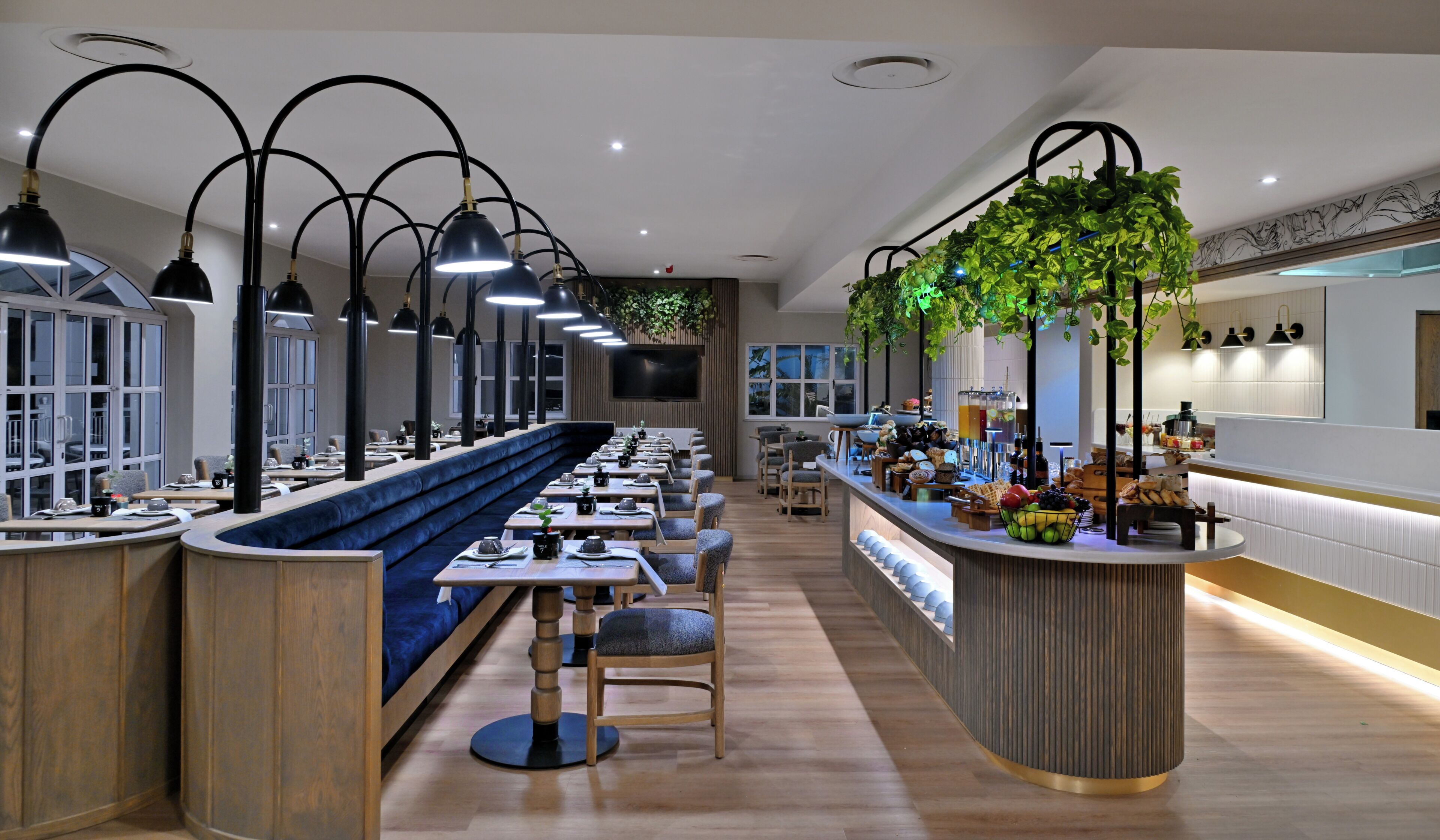 Un restaurante moderno con una barra larga, varias mesas y un área de asientos centrales.
