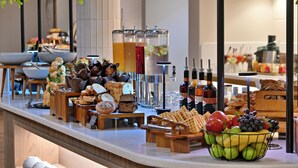 A buffet with various food items, including pastries, waffles, and a fruit bowl. - Courtyard Hotel Gqeberha (Gqeberha (Port Elizabeth))