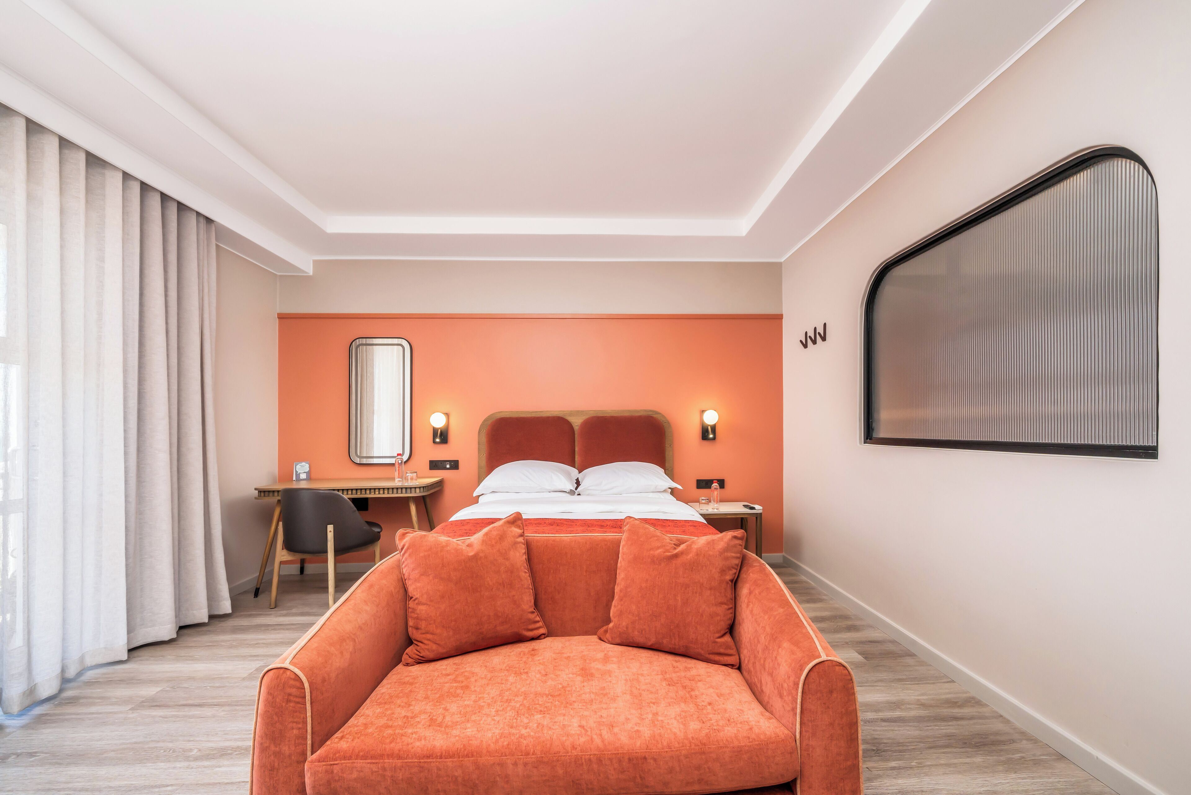 A hotel room with a bed, a desk, a chair, and a sofa.