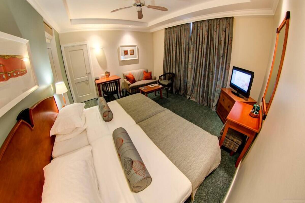 Una habitación de hotel con cama, escritorio con computadora, silla, sofá y televisión.