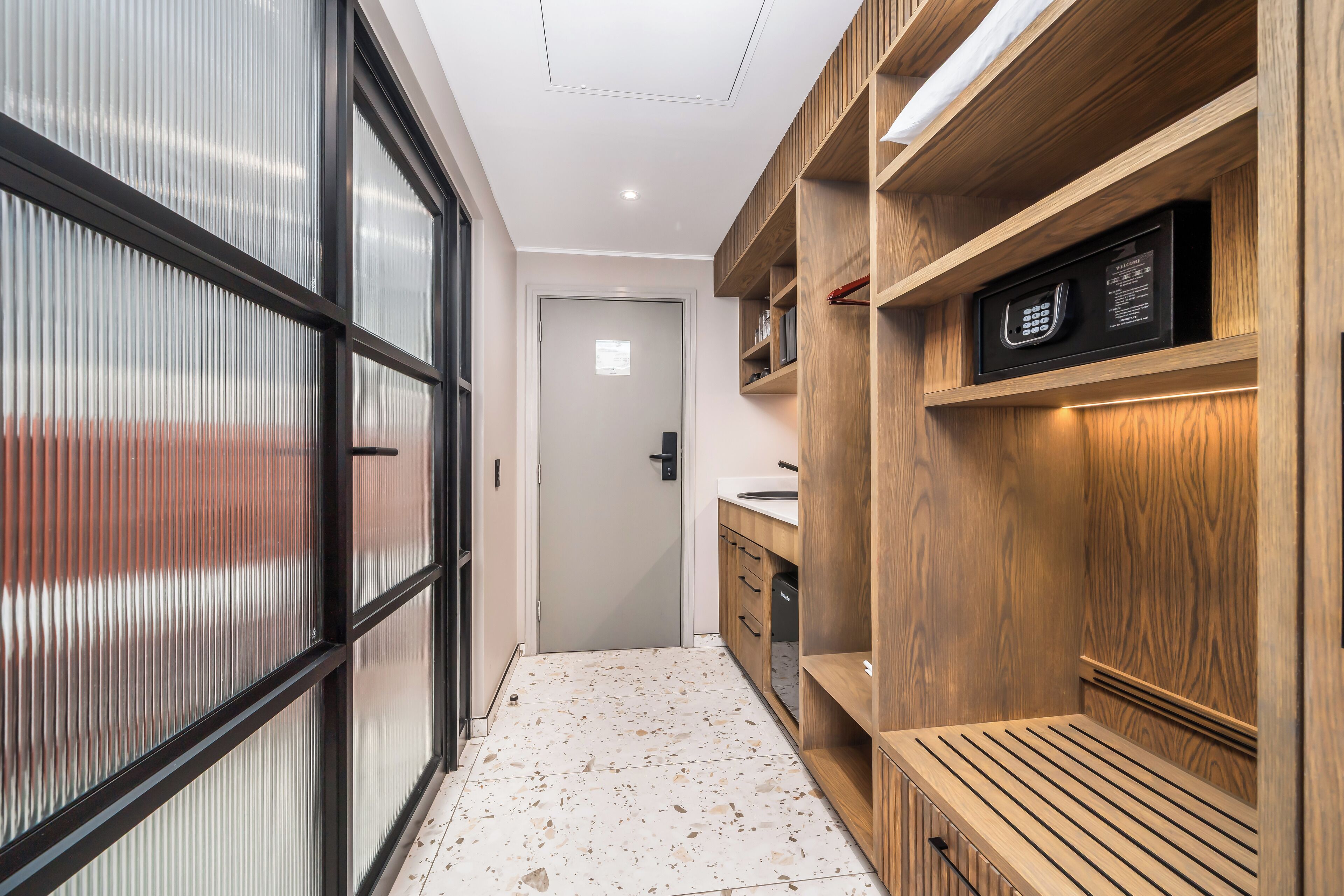 A hallway with a wooden bench, a microwave, and a door leading to another room.