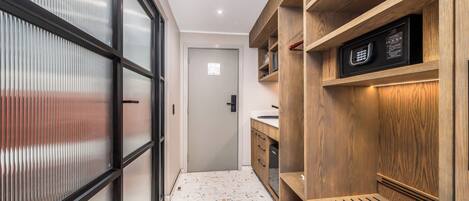 Un pasillo con un banco de madera, un microondas y una puerta que da a otra habitación.
