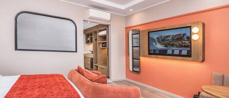 A hotel room with a bed, a seating area, a wardrobe, and a wall-mounted TV.
