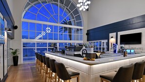 A modern kitchen with a large island, bar stools, and a view of the sky through a large window. - Courtyard Hotel Gqeberha (Gqeberha (Port Elizabeth))