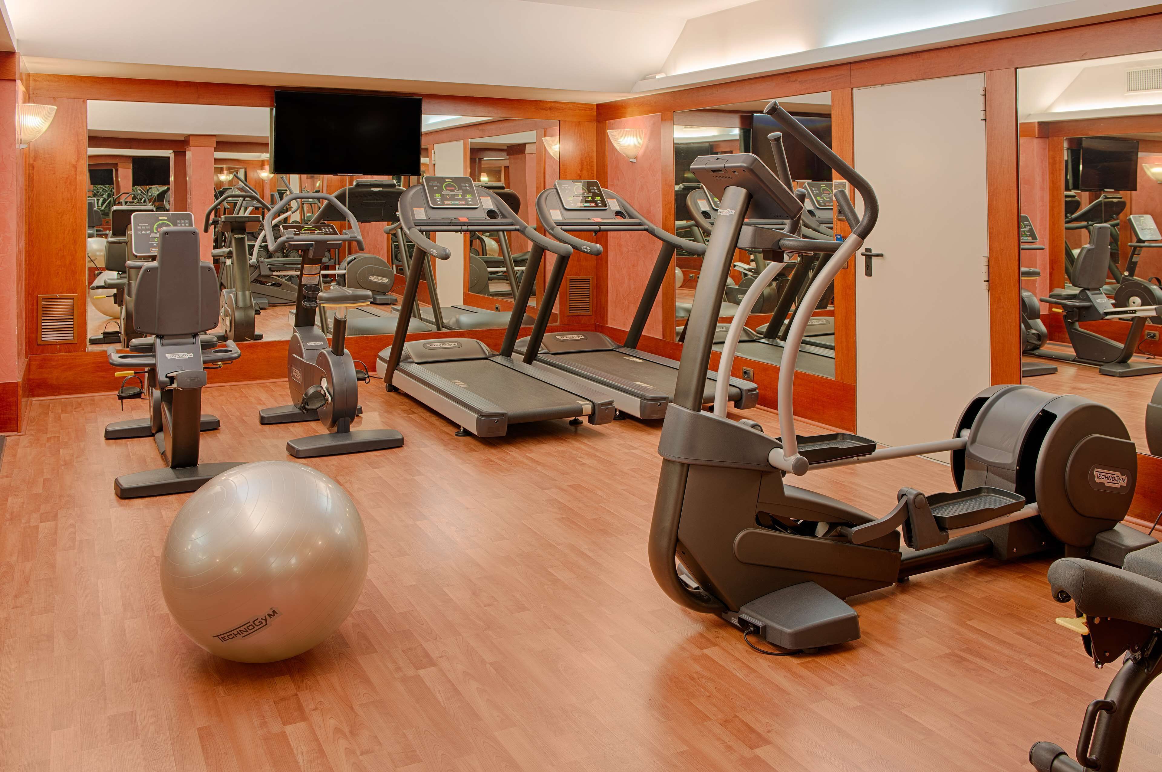 A gym with treadmills, elliptical machines, and a large exercise ball.