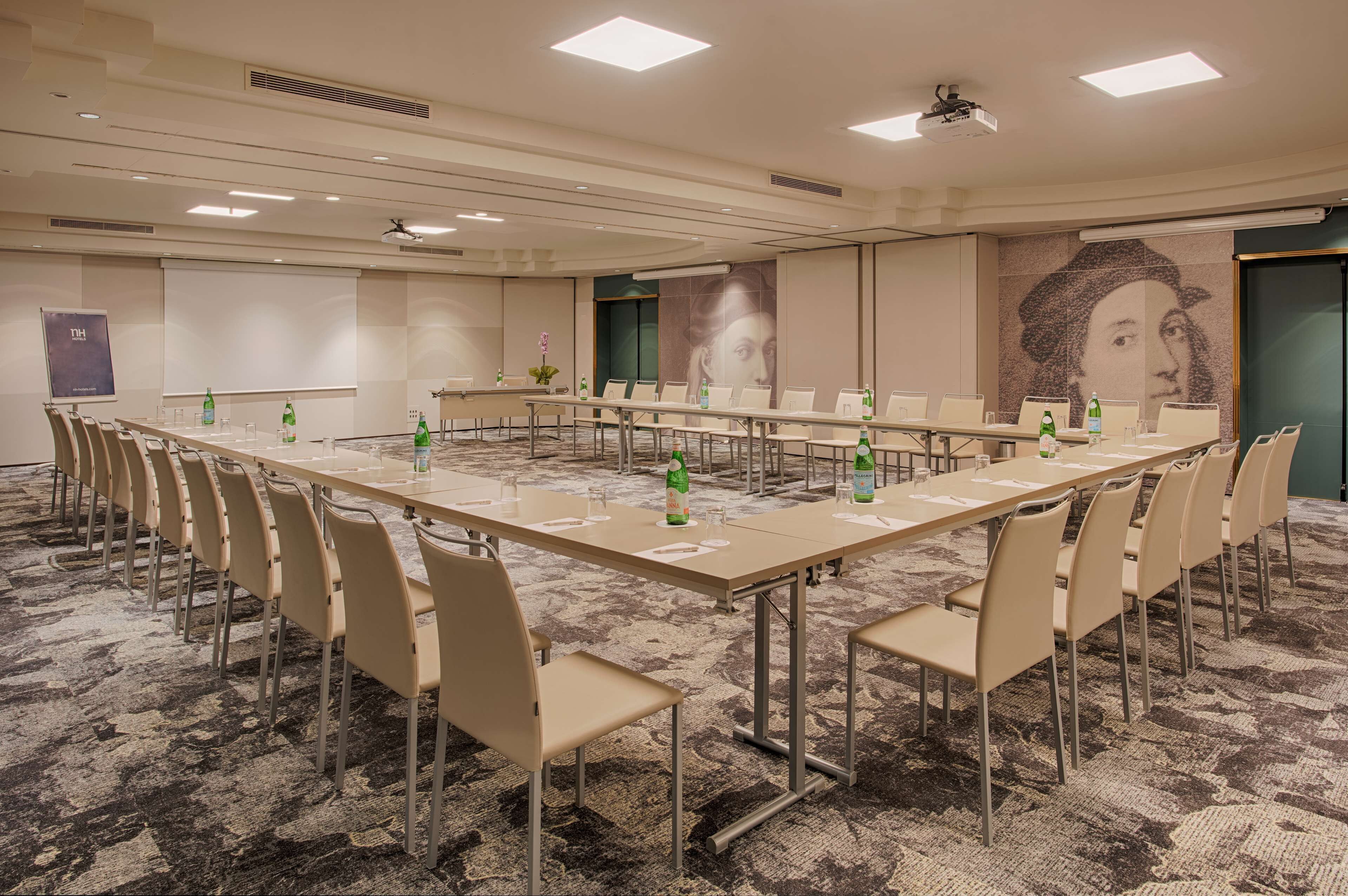 A conference room with a long table, beige chairs, and a carpeted floor.