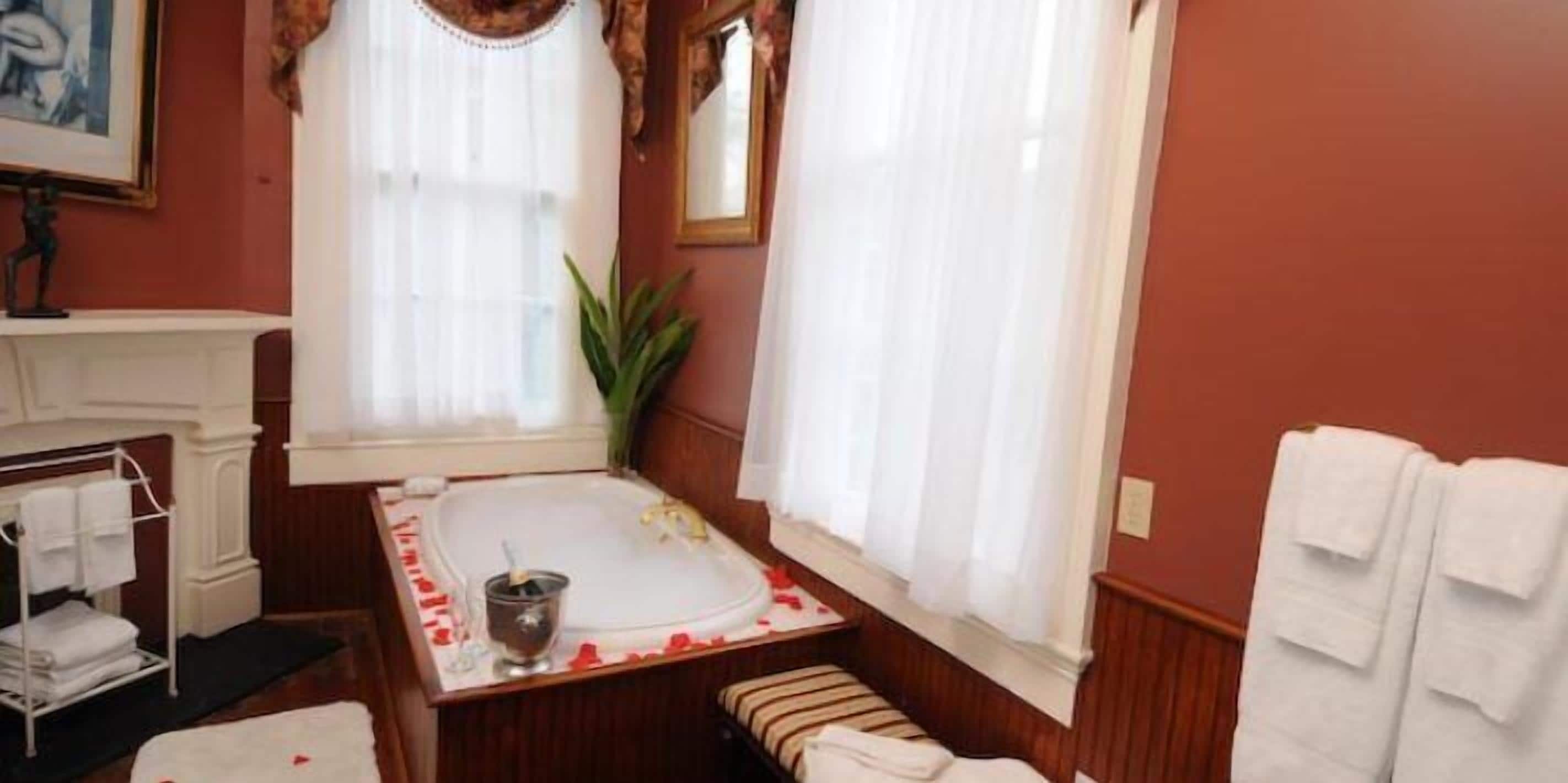 A bathroom with a bathtub, a sink, a mirror, and a towel rack.
