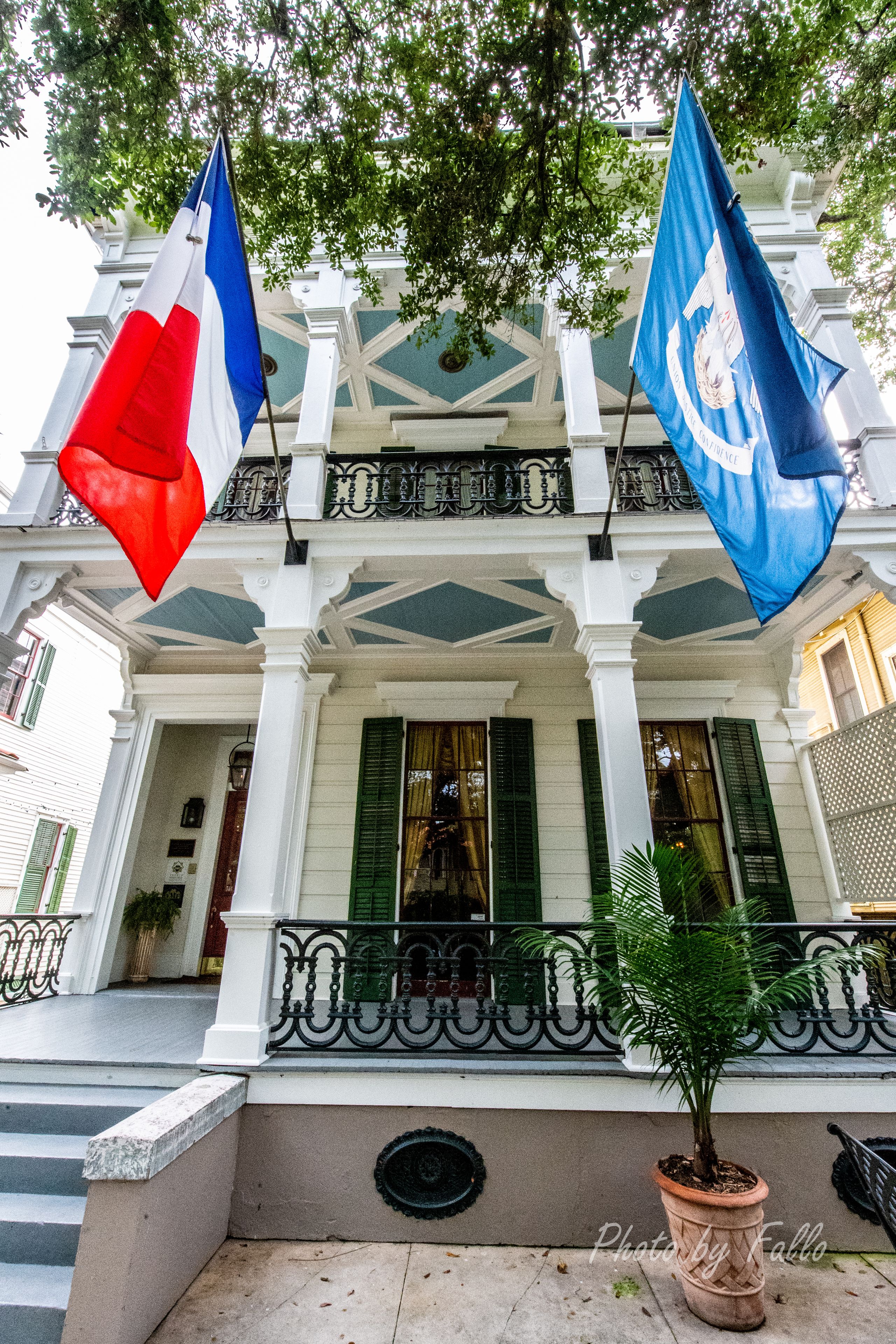 A building with a white facade, green shutters, and a balcony with a wrought iron railing.