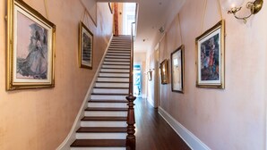 A staircase with wooden steps and a handrail, flanked by framed artwork on the walls. - Degas House (New Orleans)