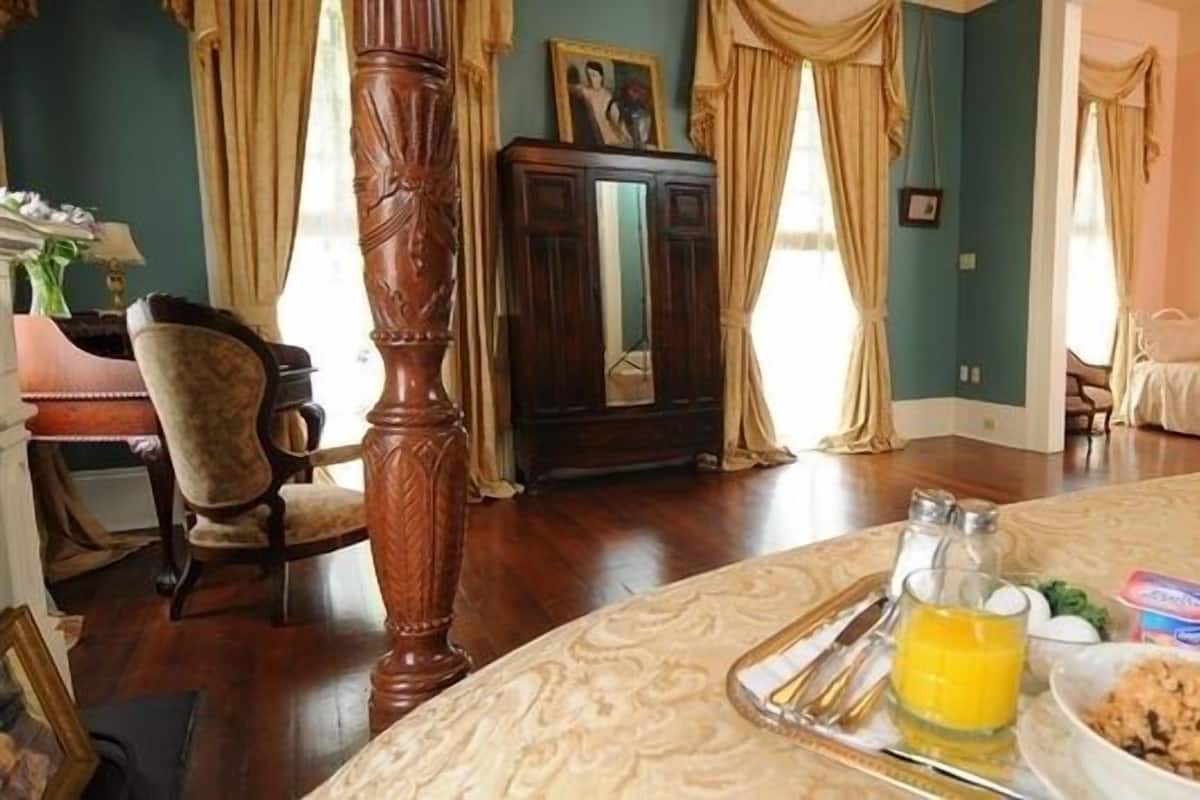 Une chambre comprenant un lit, une table à manger avec des aliments pour le petit-déjeuner, une chaise en bois et un buffet.