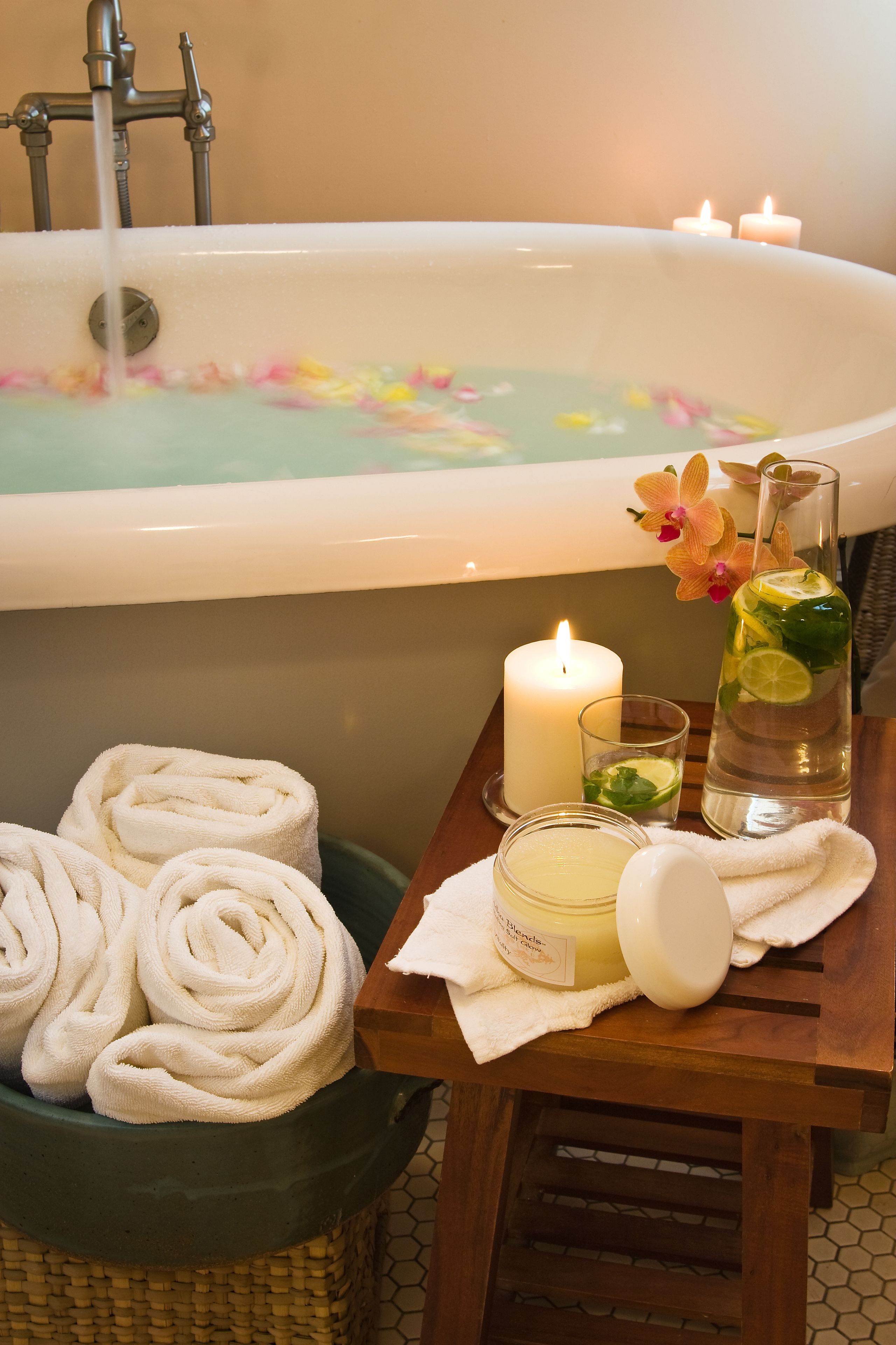 A bathroom with a bathtub, towels, candles, and a glass of water.