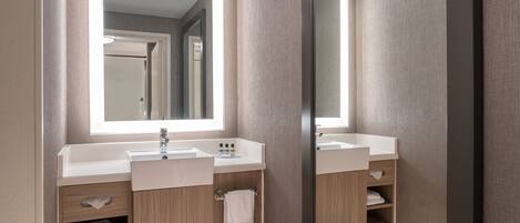 A modern bathroom with two sinks, a mirror, and wooden cabinetry.