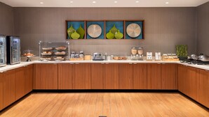 A modern kitchen with wooden cabinets, a built-in refrigerator, and a breakfast bar with various food items. - SpringHill Suites by Marriott West Mifflin (West Mifflin)