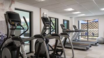 Een sportschool met loopbanden, elliptische trainers en een roeimachine.