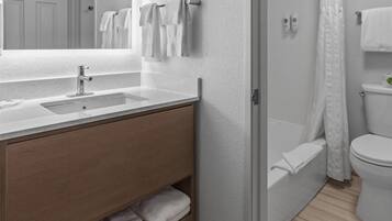 Un baño moderno con un espejo grande, un lavamanos y una zona de ducha.
